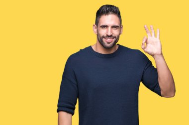 İzole arka plan el ve parmaklar ok işaretiyle yapıyor olumlu gülümseyen üzerinde kazak giyen genç yakışıklı adam. Başarılı ifade.