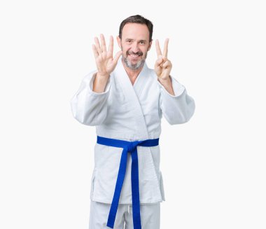 Yakışıklı orta yaş komuta sizde kimono üniforması üzerinde gösterilen arka plan izole ve parmakları ile işaret kendinden emin ve mutlu gülümseyerek süre yedi numara.
