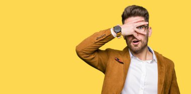 Yüz ve gözler el ile kapsayan şok bakmak gözlük takan genç yakışıklı iş adamı mahcup ifadeyle parmaklarımın arasından arıyorsunuz.