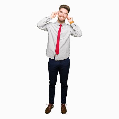 Genç yakışıklı iş adamı gülen çekerek kulaklarıyla parmaklar, komik jest. Seçmelere sorun