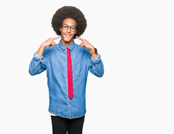 年轻的非洲裔美国商人与非洲头发戴眼镜和红色领带微笑自信显示和指向与手指的牙齿和嘴 健康理念 — 图库照片