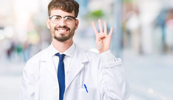 年轻的专业科学家男子穿着白色外套在孤立的背景显示和手指指向第四 同时微笑着自信和快乐 — 图库照片