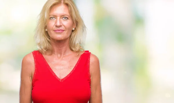 Middle age blonde woman over isolated background with serious expression on face. Simple and natural looking at the camera.