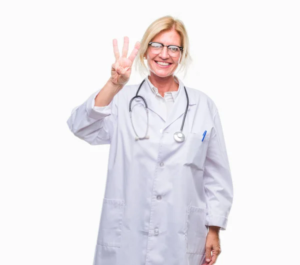 中年金发医生妇女超过孤立背景显示和指向与手指数字三同时微笑自信和快乐 — 图库照片