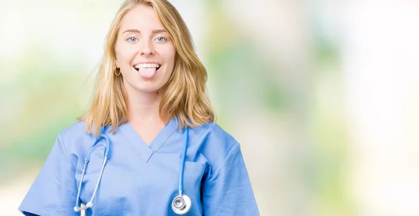 美丽的年轻医生妇女穿着医疗制服在孤立的背景伸出舌头出来快乐与有趣的表达 情感概念 — 图库照片