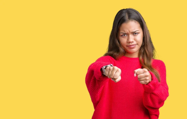 Young beautiful brunette woman wearing red winter sweater over isolated background Punching fist to fight, aggressive and angry attack, threat and violence