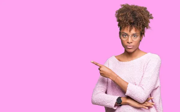 分離で眼鏡をかけて美しい若いアフリカ系アメリカ人女性が広告 深刻な穏やかな顔を示す側面手指でポインティングを背景します — ストック写真