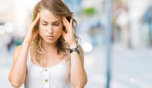 Young beautiful blonde woman over isolated background with hand on head for pain in head because stress. Suffering migraine.