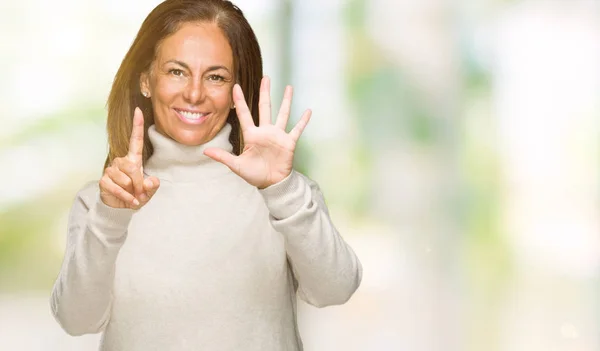 Beautiful middle age adult woman wearing winter sweater over isolated background showing and pointing up with fingers number six while smiling confident and happy.