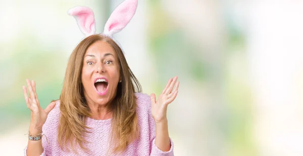 中年黑发妇女穿着复活节兔子耳朵在孤立的背景庆祝疯狂和惊讶的成功与手臂抬起和睁开眼睛尖叫兴奋 优胜者概念 — 图库照片
