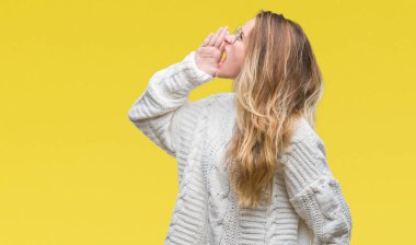 Kış kazak ve güneş gözlüğü bağırarak ve ağzı üzerinde el ile yan için çığlık izole arka plan üzerinde giyen genç güzel sarışın kadın. İletişim kavramı.