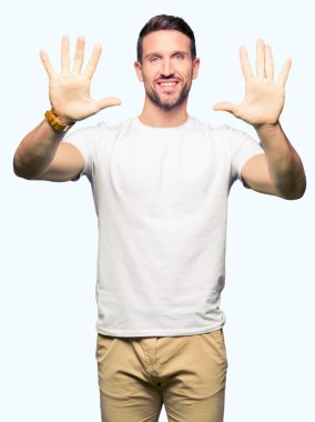 Yakışıklı adam gösterilen ve parmakları ile işaret casual beyaz t-shirt giyen kendinden emin ve mutlu gülümseyerek süre on numara.