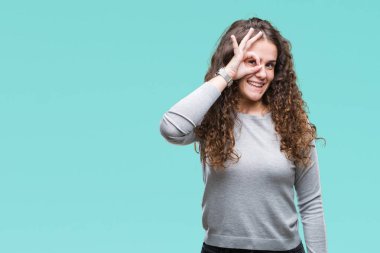 Güzel esmer kıvırcık saçlı Genç kız gülümsüyor, parmakları ile mutlu yüz üzerinden seyir göz el ile ok jest yapıyor izole arka plan üzerinde bir kazak giyiyor.