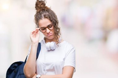 Sırt çantası ve kulaklık üzerinde seyir yorgun ve bıkkın ile depresyon sorun Çapraz kollar ile izole arka plan düşünme giyen genç esmer öğrenci kız.