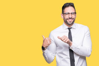 Üzerinde gözlük takan genç yakışıklı iş adamı izole arka plan emin gülümseyen arkasından el ve kadar başparmak ile işaret