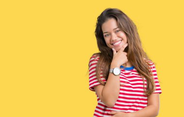 Emin çapraz kollar ve çeneme kaldırdı el ile gülümseme ile kameraya bakarak izole arka plan üzerinde tişört giyen genç güzel esmer kadın çizgili. Pozitif düşünce.