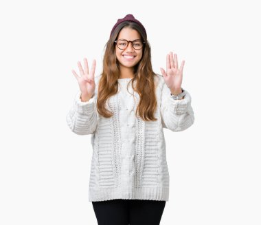 Genç güzel esmer hipster kadın gözlük ve kış şapka gösterilen ve parmakları ile işaret izole arka plan üzerinde dokuz kendinden emin ve mutlu gülümseyerek iken numara.