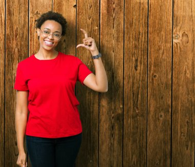 Güzel genç Afro-Amerikan kadın gözlük gülümseyen izole arka plan ve süre seyir ve kamera boyutu işaret parmaklarıyla yapıyor el ile kendinden emin eller üzerinde. Ölçü kavramı.