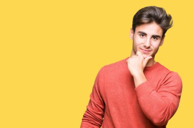 Yakışıklı delikanlı emin çapraz kollar ve çeneme kaldırdı el ile gülümseme ile kameraya bakarak izole arka plan üzerinde. Pozitif düşünce.