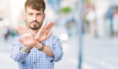 Genç yakışıklı iş adamı izole arka plan ret ifade geçiş silah ve avuç içi eksi işareti, kızgın surat yapıyor