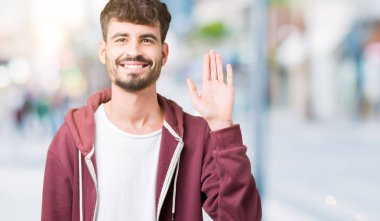 Yakışıklı delikanlı izole arka plan Waiving mutlu selam söyleyerek üzerinde ve gülümseyen, dostça karşılama jest