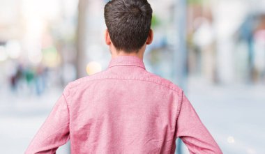 Yakışıklı delikanlı izole arka plan ayakta geriye doğru uzakta silah ile vücut üzerinde seyir üzerinde pembe gömlek giymiş