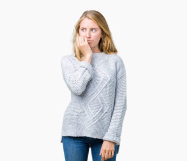 Stresli ve gergin elle çivi ısırma ağzına bakarak izole arka plan üzerinde kış kazak giyen güzel genç kadın. Anksiyete sorunu.