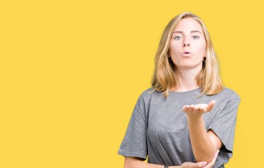 Bir öpücük el ile güzel ve seksi olmak hava üfleme kamera bakarak izole arka plan üzerinde büyük boy rahat t-shirt giyen güzel ve genç birbayan. Aşk ifade.