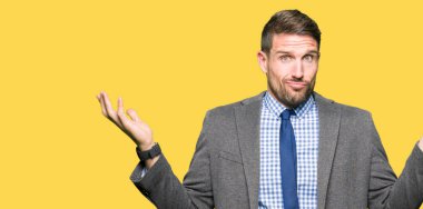 Yakışıklı iş adamı giyen takım elbise ve clueless ve şaşkın bir ifadeyle kollar ve eller kaldırdı kravat. Şüphe kavramı.