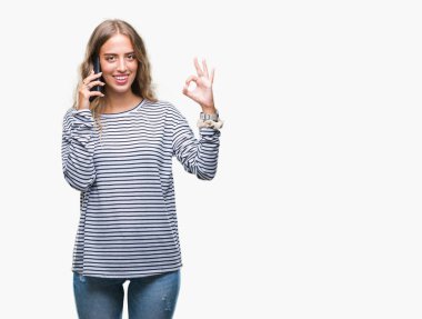 Güzel genç sarışın kadın smarpthone üzerinde parmak, mükemmel sembolü ile ok işareti yapıyor izole arka plan üzerinde söz