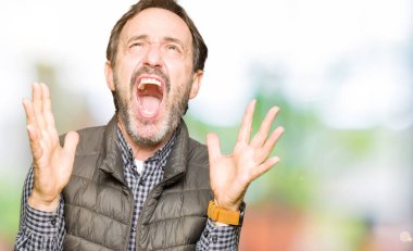 Kış yelek çılgın ve kızgın bağırarak ve agresif ifade ve silah kaldırdı bağırmaya giyen orta yaş yakışıklı adam. Hayal kırıklığı kavramı.