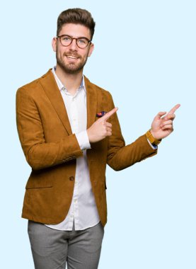 Gülümseyen ve iki elleri ve parmakları ile tarafına işaret kamera bakarak gözlüklü genç yakışıklı iş adamı.