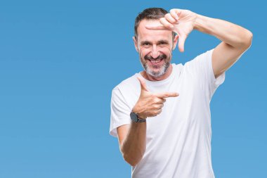 Elle yapma çerçeve ve parmakları ile mutlu yüz gülümseyen izole arka plan üzerinde beyaz t-shirt giyen orta yaş ağarmış komuta sizde. Yaratıcılık ve Fotoğrafçılık kavramı.