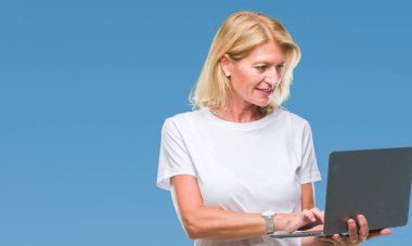 Acımak yüz ciddi düşünüyorum üstünde kendine güvenen bir ifade ile izole arka plan üzerinde bilgisayar dizüstü kullanan orta yaş sarışın kadın