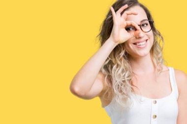 Güzel genç sarışın kadın gülümsüyor, parmakları ile mutlu yüz üzerinden seyir göz el ile ok jest yapıyor izole arka plan üzerinde gözlük.