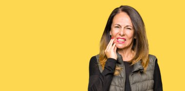 Diş ağrısı veya dişlerde dişlerle ilgili hastalık nedeniyle ağız acı ifadesi ile el ile dokunmak kış yelek giyen güzel orta yaş kadın. Diş hekimi kavramı.