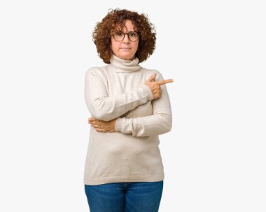 Güzel orta ager kadın kıdemli giyen boğazlı kazak ve gözlük izole üzerinde işaretçi el parmak tarafı gösteren reklam, ciddi ve sakin yüz için arka plan