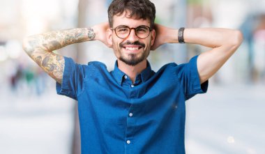 Genç yakışıklı adam gözlük izole üzerinde arka plan dinlenirken ve germe kollar ve eller baş ve boyun arkasında ile mutlu gülümseyerek