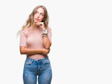 Güzel sarışın genç kadın elle çene düşünme hakkında soru, dalgın ifade izole arka plan üzerinde. Düşünceli yüzüyle gülümsüyor. Şüphe kavramı.