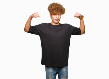 Yakışıklı genç afro saçlı siyah t-shirt gösteren kol kasları gururlu gülümseyen giyiyor. Fitness kavramı.