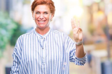 Atrractive üst düzey beyaz Kızıl saçlı kadın gösterilen ve parmakları ile işaret izole arka plan üzerinde üçüncü ise kendinden emin ve mutlu gülümseyerek.