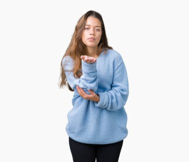 Bir öpücük el ile güzel ve seksi olmak hava üfleme kamera bakarak izole arka plan üzerinde mavi kış kazak giyen genç güzel esmer kadın. Aşk ifade.