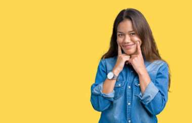 Genç güzel esmer kadın giyiyor mavi kot gömlek izole üzerinde arka plan gülen açık ağız ile parmak işaret ve neşeli gülümseme zorlamadan