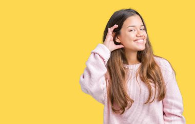 Bir işitme söylenti ya da dedikodu için dinleme kulak üzerinde el ile gülümseyen izole arka plan üzerinde pembe kış kazak giyen genç güzel esmer kadın. Sağırlık kavramı.