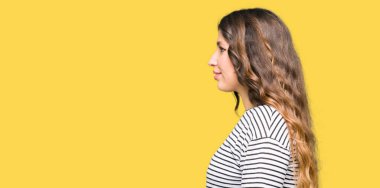 Genç güzel kadın giyiyor çizgili süveter tarafa bakarak dinlenmek doğal yüz emin gülümseme ile pozuyla profil.