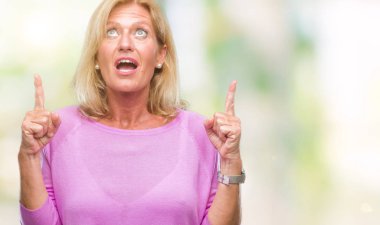 Orta yaş sarışın kadın izole arka plan üzerinden hayran ve yukarıya bakıp parmakları ile işaret şaşırttı ve silah kaldırdı.