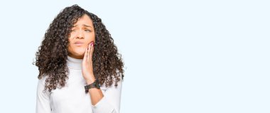 Genç güzel kadın kıvırcık saçlı diş ağrısı veya dişlerde dişlerle ilgili hastalık nedeniyle ağız acı ifadesi ile el ile dokunmak boğazlı kazak giyiyor. Diş hekimi kavramı.