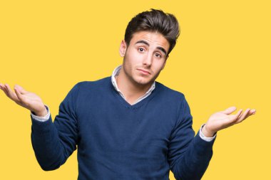 Genç yakışıklı iş adamı izole arka plan clueless ve şaşkın bir ifadeyle kollar ve eller ortaya çıkar üzerinden. Şüphe kavramı.