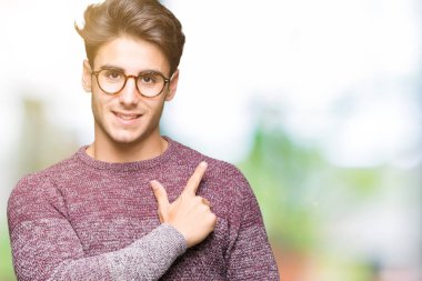 İzole arka neşeli bir gülümseme ile el ve parmak kadar yan yüzünde mutlu ve doğal ifade ile işaret yüz üzerinden gözlüklü genç yakışıklı adam