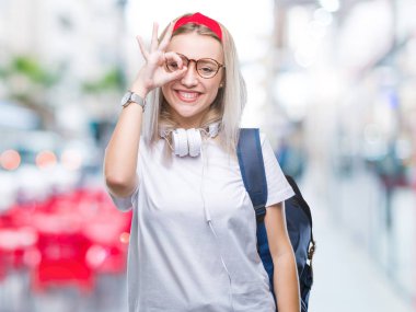 Genç sarışın öğrenci kadın gözlük ve sırt çantası el gülümseyen, ok jest yapıyor izole arka plan üzerinde göz parmakları ile mutlu yüz üzerinden seyir.